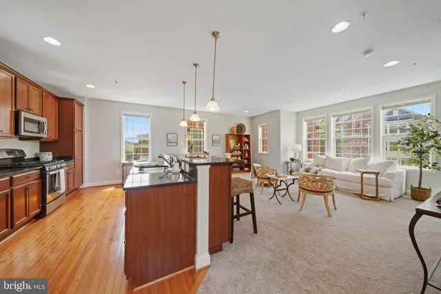 a view of a dining room and livingroom with furniture wooden floor a rug a flat screen tv a rug and a chandelier