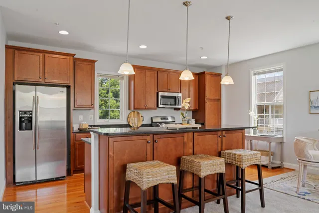 a kitchen with granite countertop a table chairs refrigerator and microwave