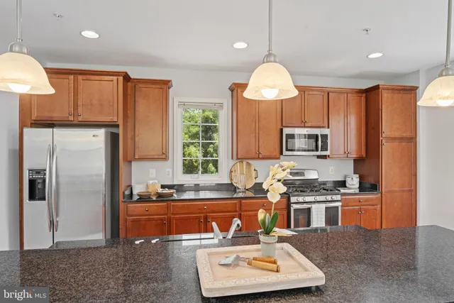 a kitchen with stainless steel appliances granite countertop a sink refrigerator stove and microwave