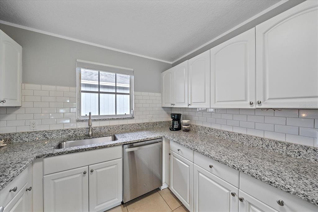 772 Locklear Avenue Sarasota, FL 34237 - Photo 26 of 40 a kitchen with granite countertop white cabinets sink and window