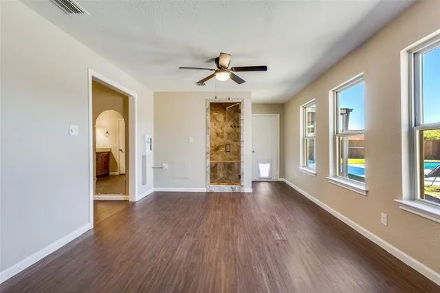 a view of an empty room with a window and wooden floor