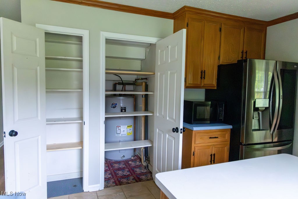 3333 Dayton Road Madison, OH 44057 - Photo 14 of 48 Kitchen featuring stainless steel fridge with ice dispenser, black microwave, strapped water heater, and brown cabinetry
