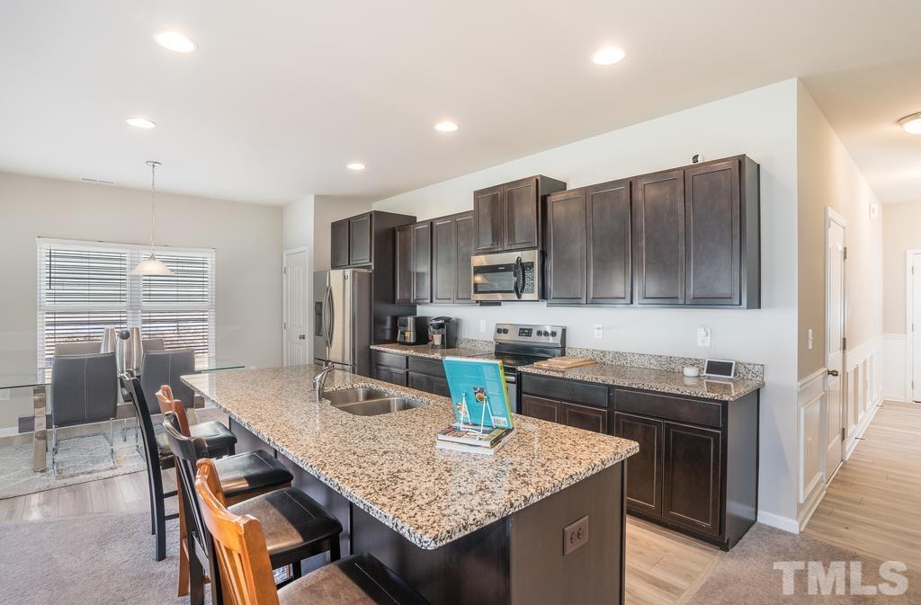 6801 Resting Grove Road Raleigh, NC 27610 - Photo 11 of 28 a kitchen with a stove a sink a refrigerator and chairs