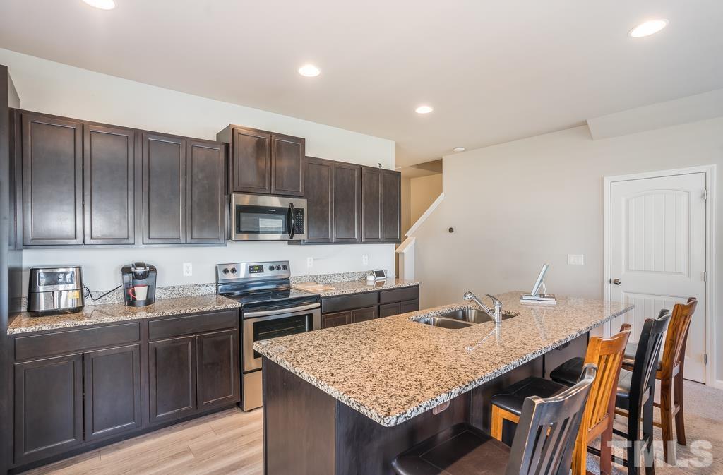 6801 Resting Grove Road Raleigh, NC 27610 - Photo 12 of 28 a kitchen with stainless steel appliances granite countertop a kitchen island hardwood floor sink stove and cabinets
