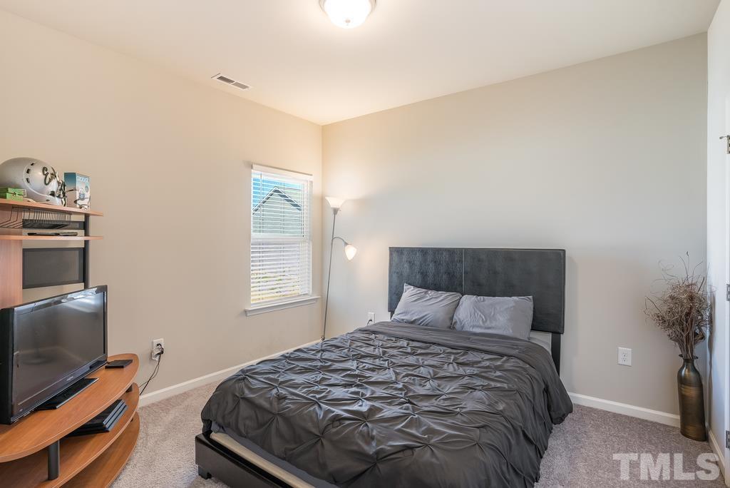 6801 Resting Grove Road Raleigh, NC 27610 - Photo 20 of 28 a bedroom with a bed and flat tv screen on a dresser