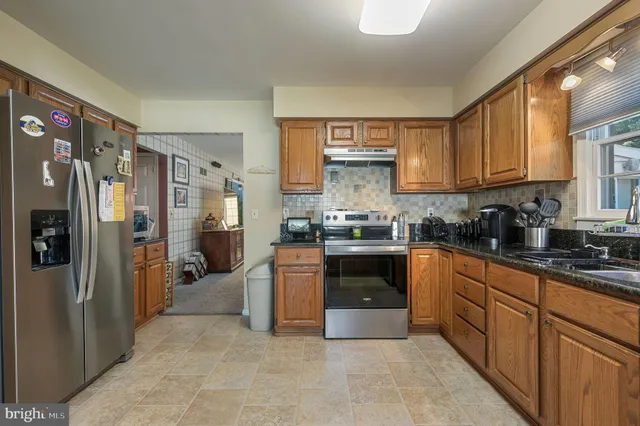 a kitchen with granite countertop a refrigerator stove top oven and sink