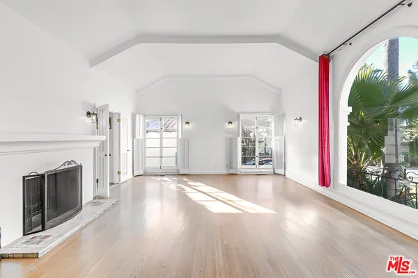 a view of an empty room with window and wooden floor