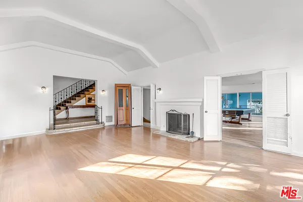 a view of a livingroom with wooden floor and kitchen view