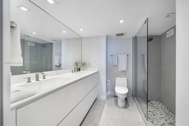a bathroom with a sink a toilet a shower and a mirror
