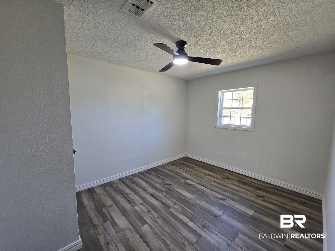 821 Dailey Street Brewton, AL 36426 - Photo 13 of 17 Empty room with dark wood-type flooring, a textured ceiling, and ceiling fan