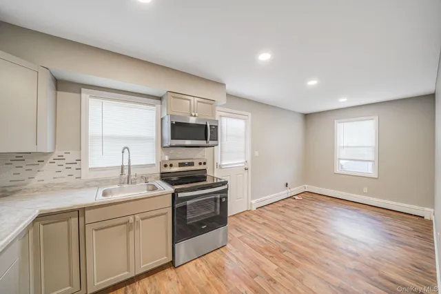 a kitchen with a sink wooden floor and stainless steel appliances