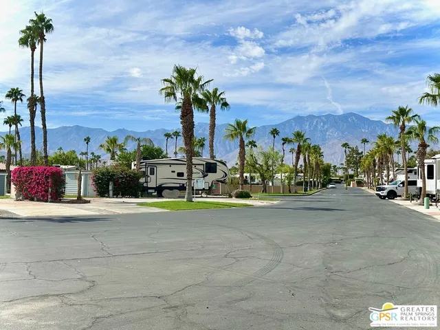 a white house with a yard and palm trees