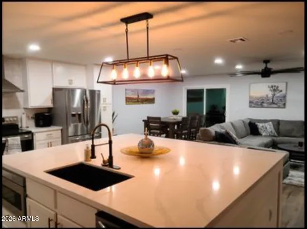 a kitchen with a chandelier a sink and refrigerator