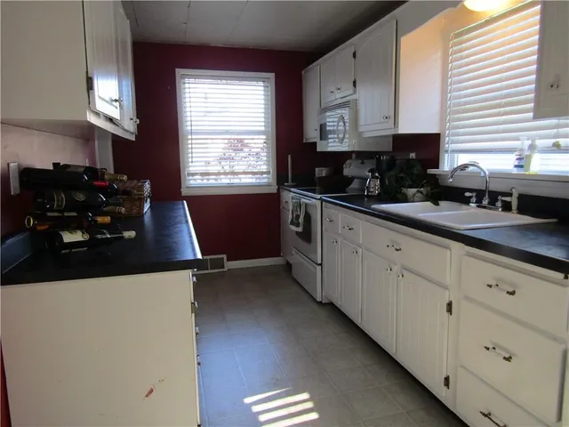 a kitchen with stainless steel appliances a sink a stove a refrigerator white cabinets and wooden floor