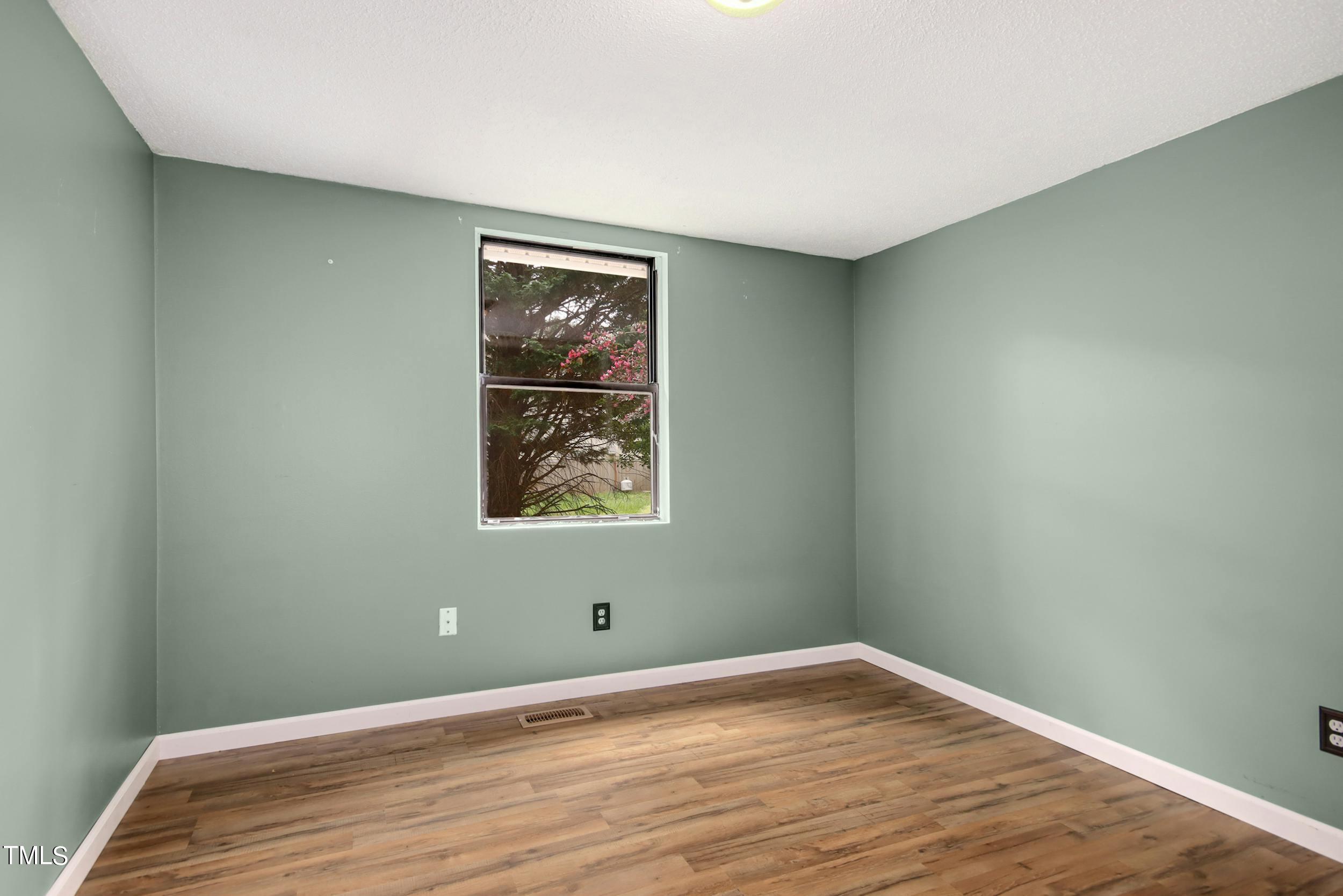 2609 Carpenter Pond Road Raleigh, NC 27613 - Photo 14 of 33 a view of an empty room with wooden floor and a window