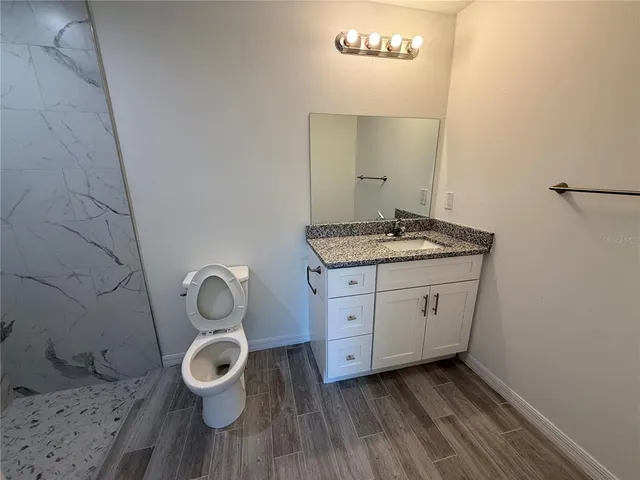 a bathroom with a granite countertop toilet sink and mirror