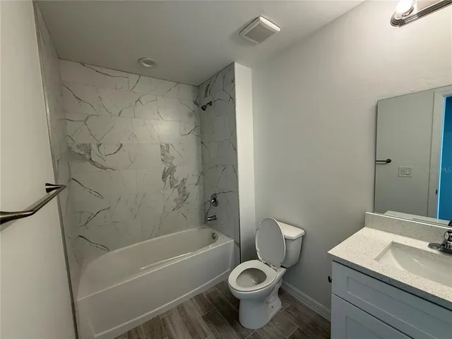 a bathroom with a granite countertop toilet a sink and a bathtub
