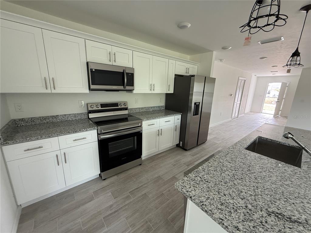 5290 Arley Road North Port, FL 34288 - Photo 6 of 26 a kitchen with stainless steel appliances granite countertop a stove a sink and a refrigerator