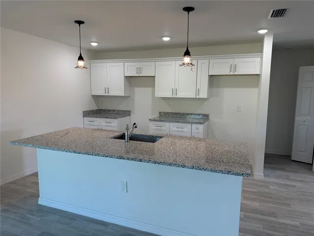 a kitchen with kitchen island granite countertop a sink a center island a stove and cabinets