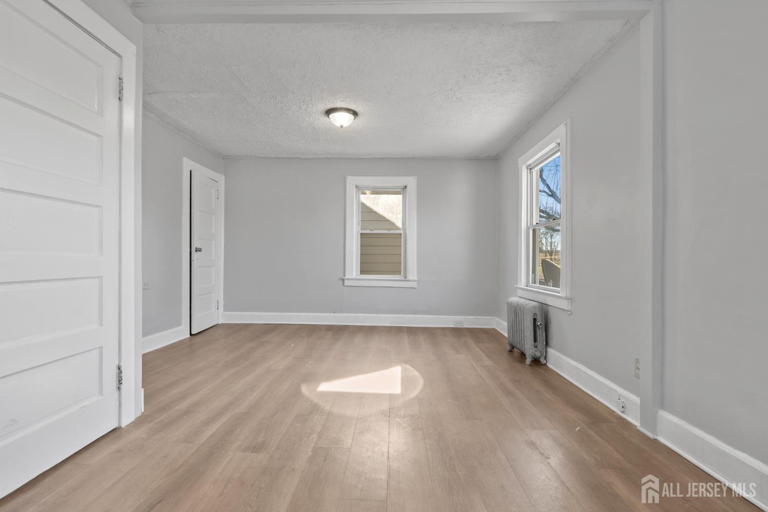 83 May Street Irvington, NJ 07111 - Photo 18 of 27 an empty room with wooden floor and windows
