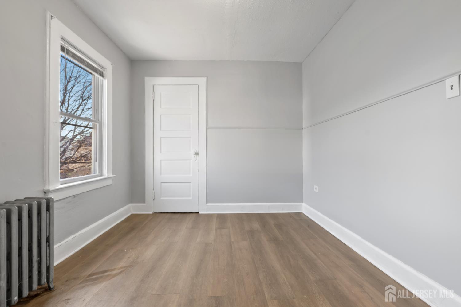 83 May Street Irvington, NJ 07111 - Photo 26 of 27 an empty room with wooden floor and windows