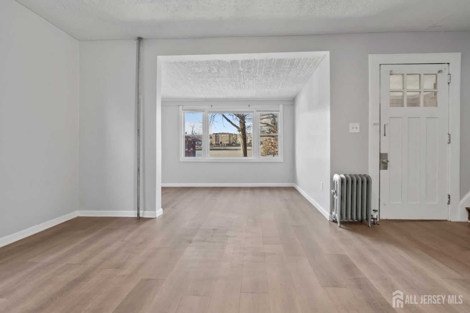83 May Street Irvington, NJ 07111 - Photo 6 of 27 an empty room with wooden floor and windows