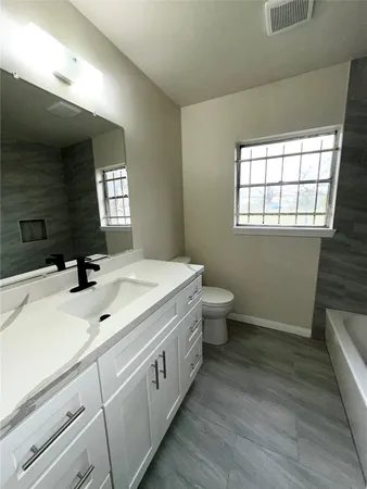 a spacious bathroom with a double vanity sink toilet and a window