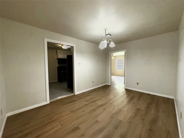 an empty room with wooden floor and chandelier