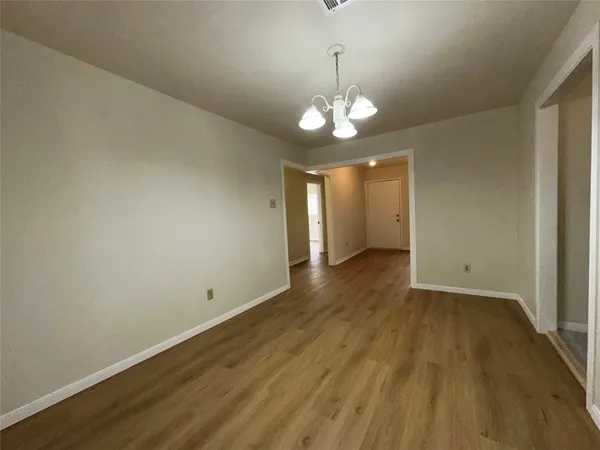 an empty room with wooden floor and chandelier