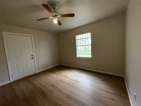 an empty room with wooden floor fan and windows