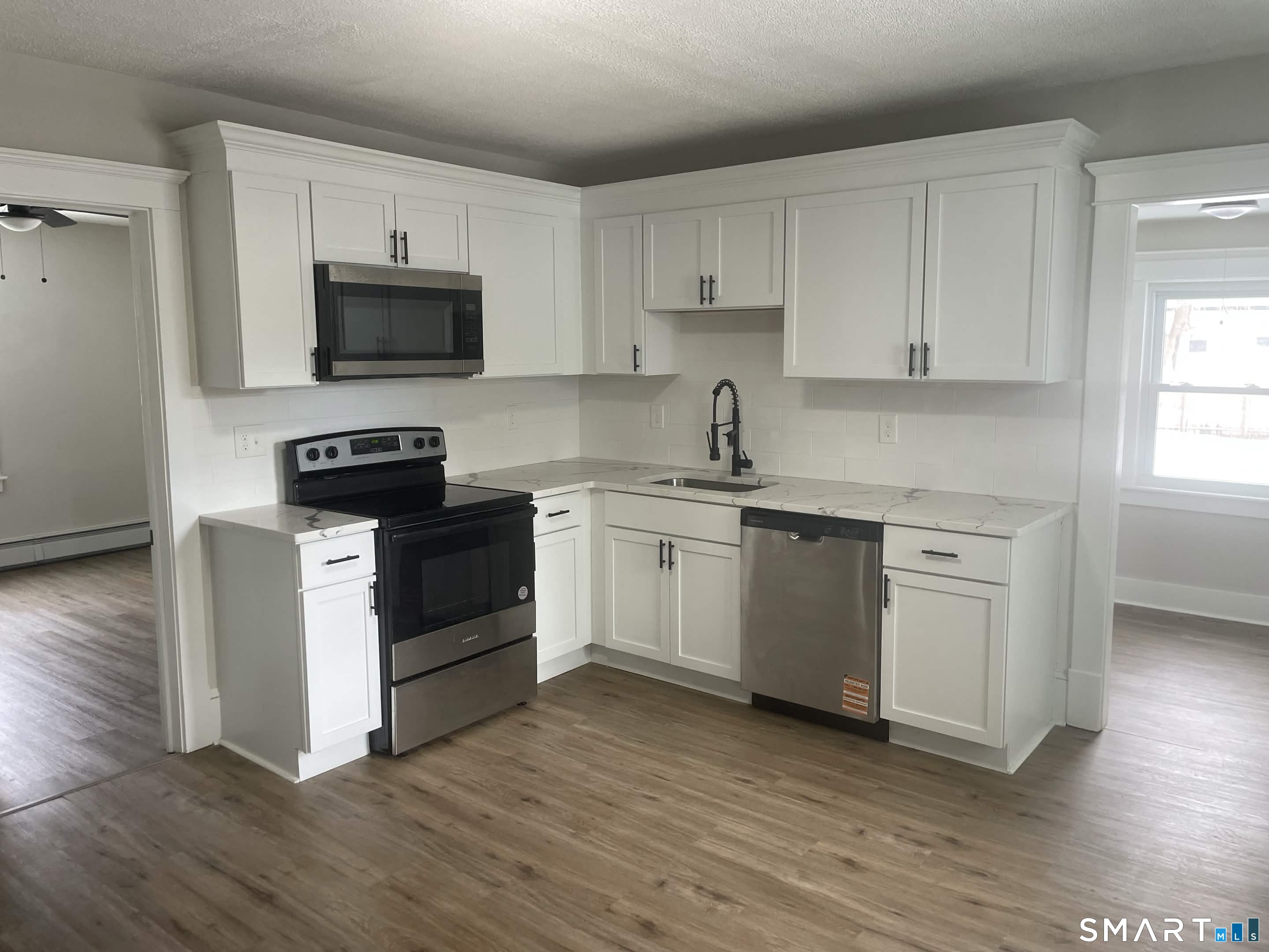 82 Windsor Street, Unit 1 Enfield, CT 06082 - Photo 1 of 1 a kitchen with white cabinets stainless steel appliances and wooden floor