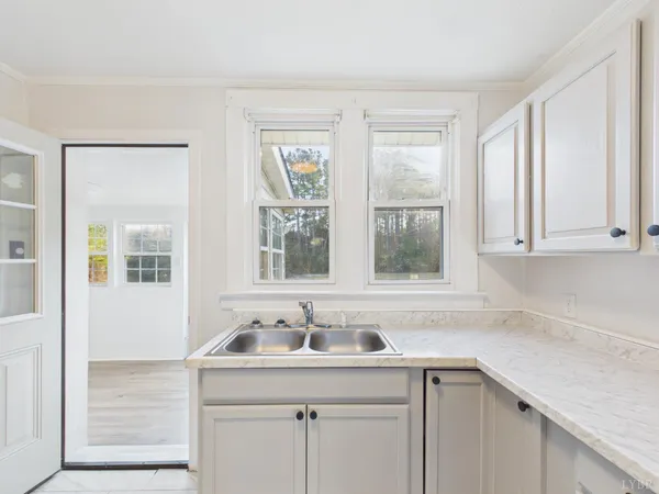 a white kitchen with a sink window and cabinets