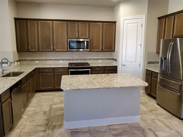 a kitchen with stainless steel appliances granite countertop a stove a refrigerator and a sink