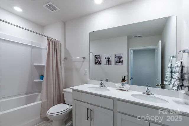 a bathroom with a double vanity sink toilet mirror and shower