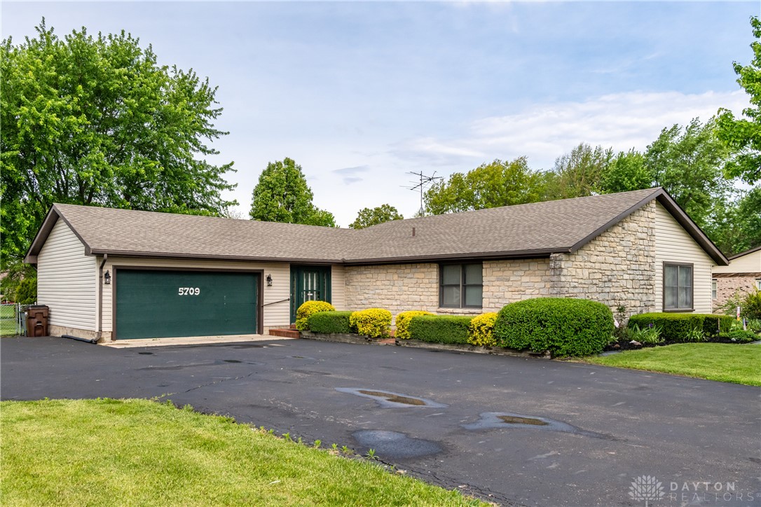 This charming home showcases a durable shingle roof and a well-maintained asphalt driveway, complementing its classic facade.