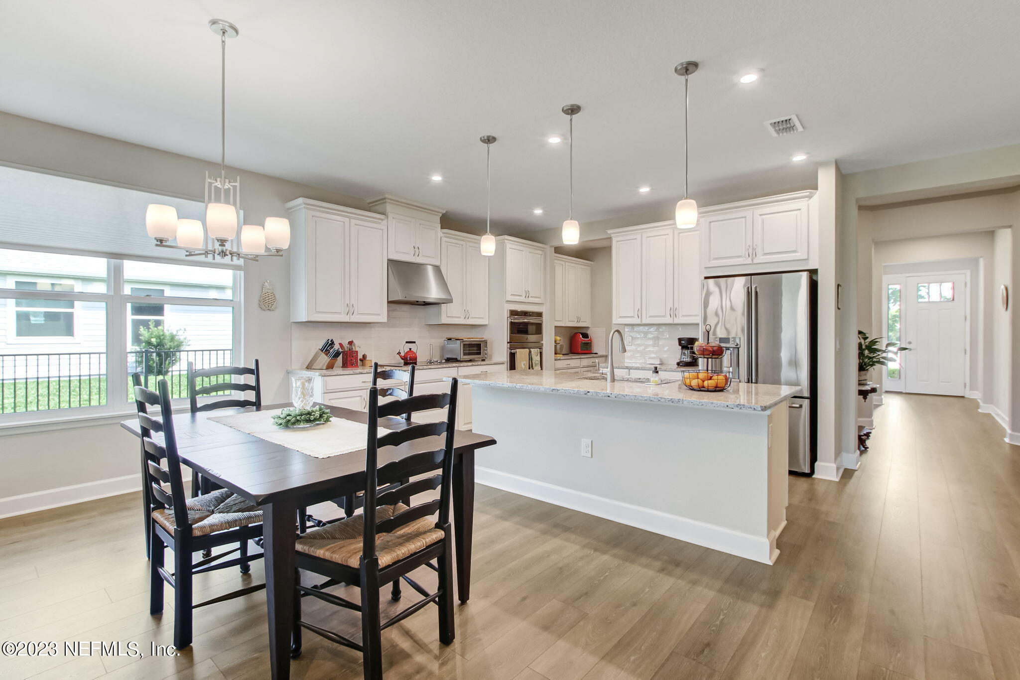 85276 Berryessa Way Yulee, FL 32097 - Photo 12 of 42 a kitchen with stainless steel appliances kitchen island granite countertop a dining table chairs and white cabinets