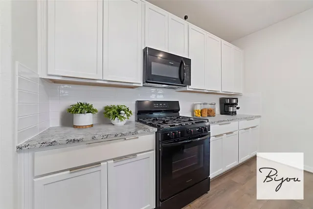 a kitchen with stainless steel appliances granite countertop white cabinets a stove top oven and granite counter tops