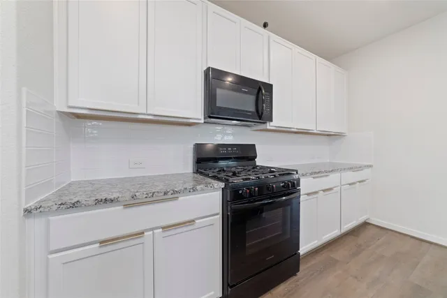 a kitchen with stainless steel appliances granite countertop white cabinets stove top oven and granite counter top