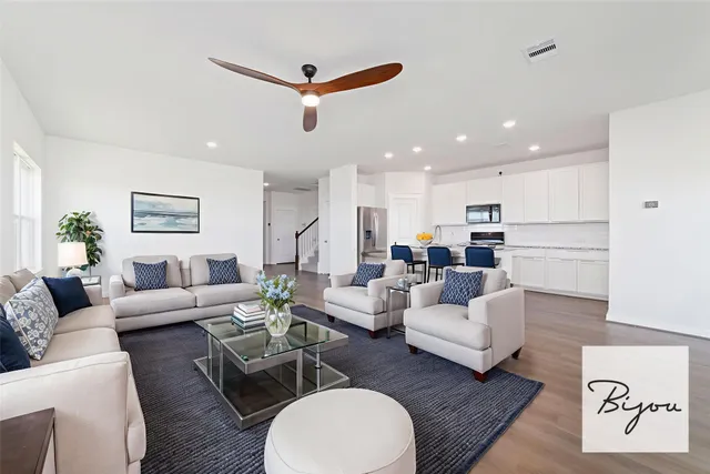 a living room with furniture kitchen view and a wooden floor
