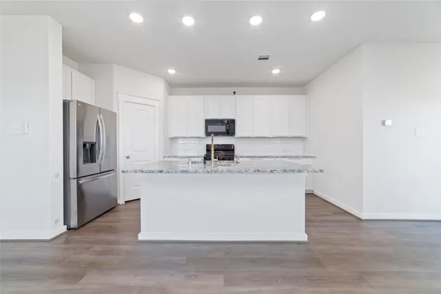 a kitchen with kitchen island stainless steel appliances a sink and a refrigerator