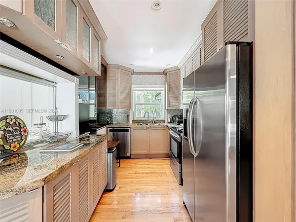 a kitchen with granite countertop a sink a stove top oven a wooden floor