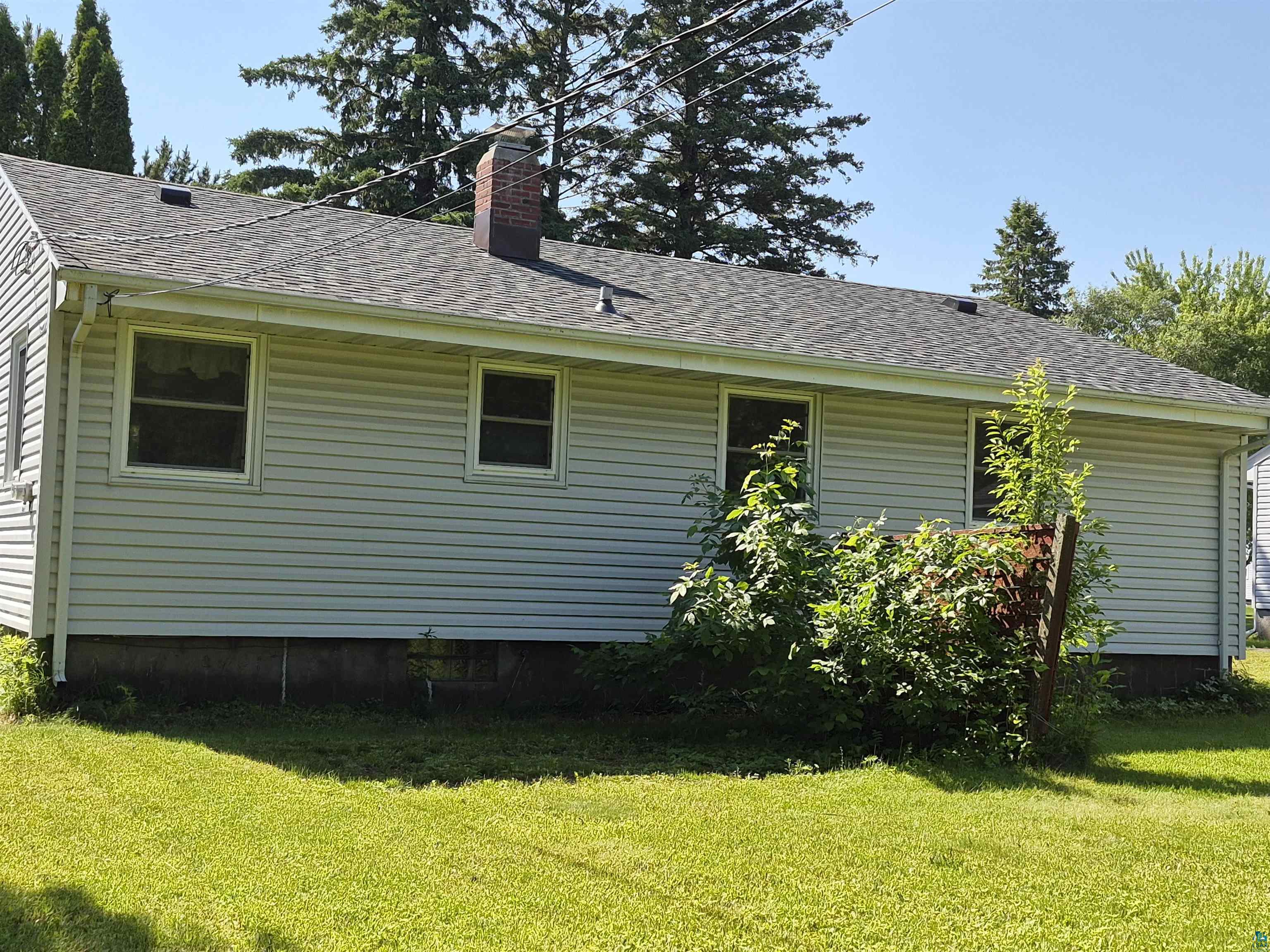 2109 West 22nd Street Duluth, MN 55811 - Photo 4 of 29 Light gray siding exterior with a shingled roof, featuring a brick chimney and multiple windows