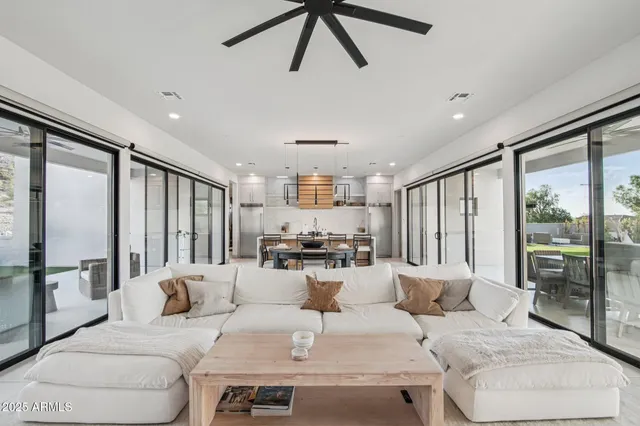 a living room with furniture ceiling fan and a large window