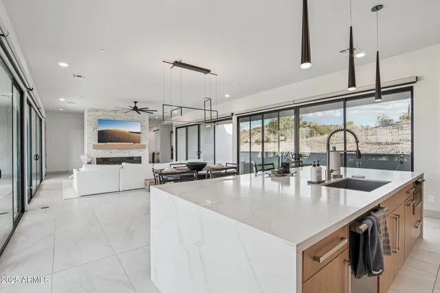 a kitchen with stainless steel appliances kitchen island granite countertop a dining table chairs and a refrigerator