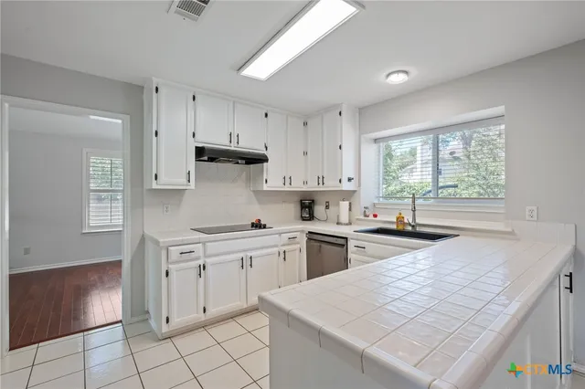 a kitchen with granite countertop white cabinets white appliances a sink and a window