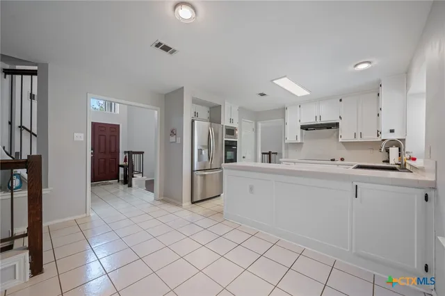 a large white kitchen with cabinets and stainless steel appliances
