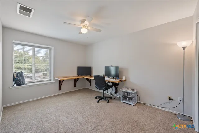 a view of a workspace with furniture and a window