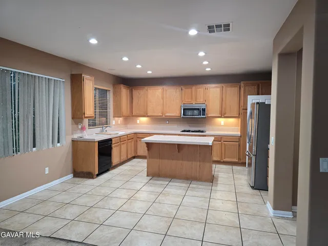 a large kitchen with a large counter top stainless steel appliances and cabinets