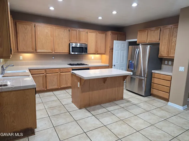 a kitchen with stainless steel appliances granite countertop a stove top oven a sink and a refrigerator