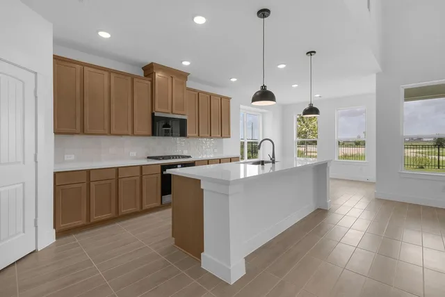 a large kitchen with a large counter top a sink stainless steel appliances and cabinets